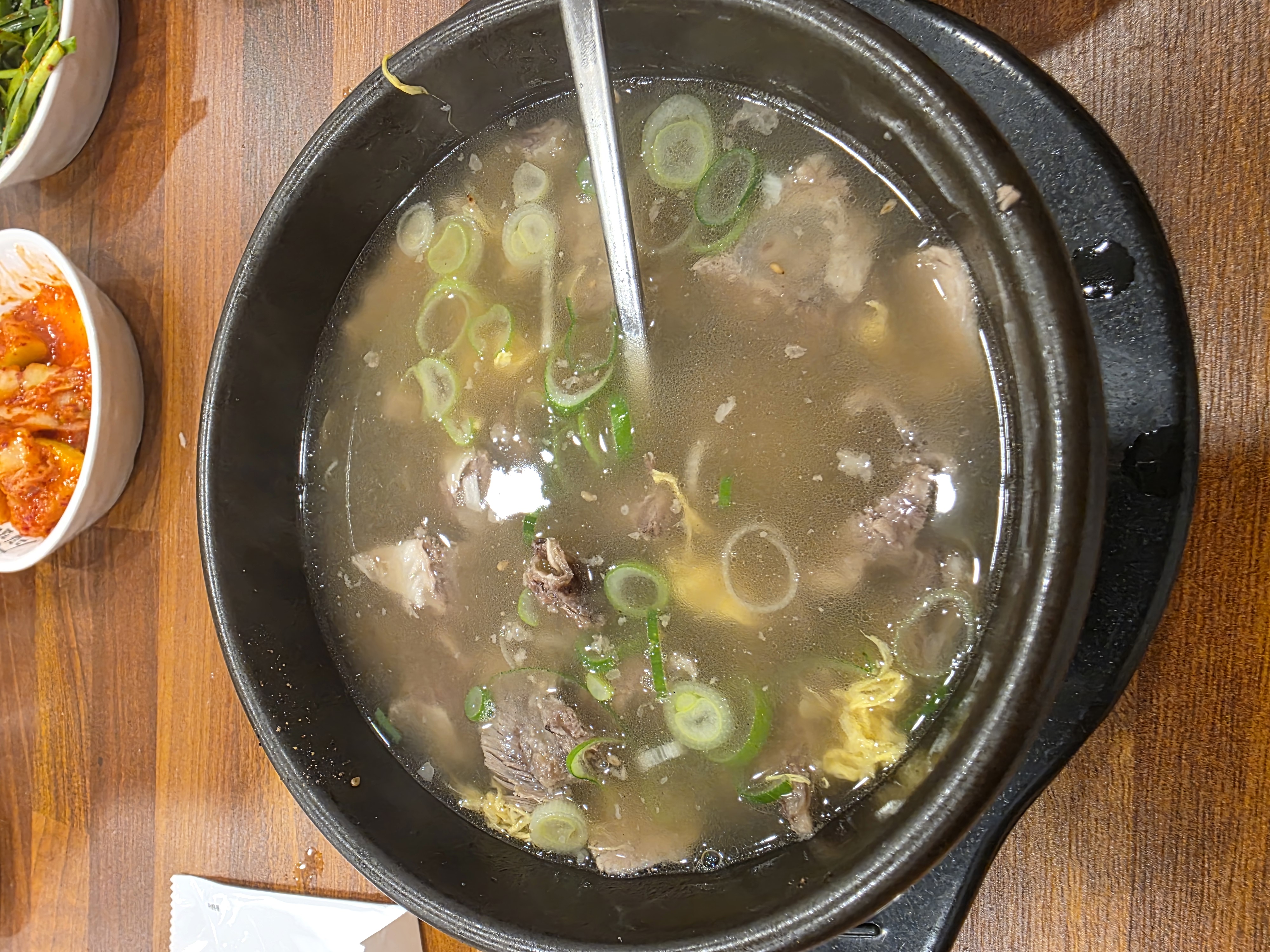 골목 안쪽 갈비탕집에서 혼자 받은 상, 검은 무쇠 그릇에 담긴 맑은 갈비탕과 김치 파무침 종지