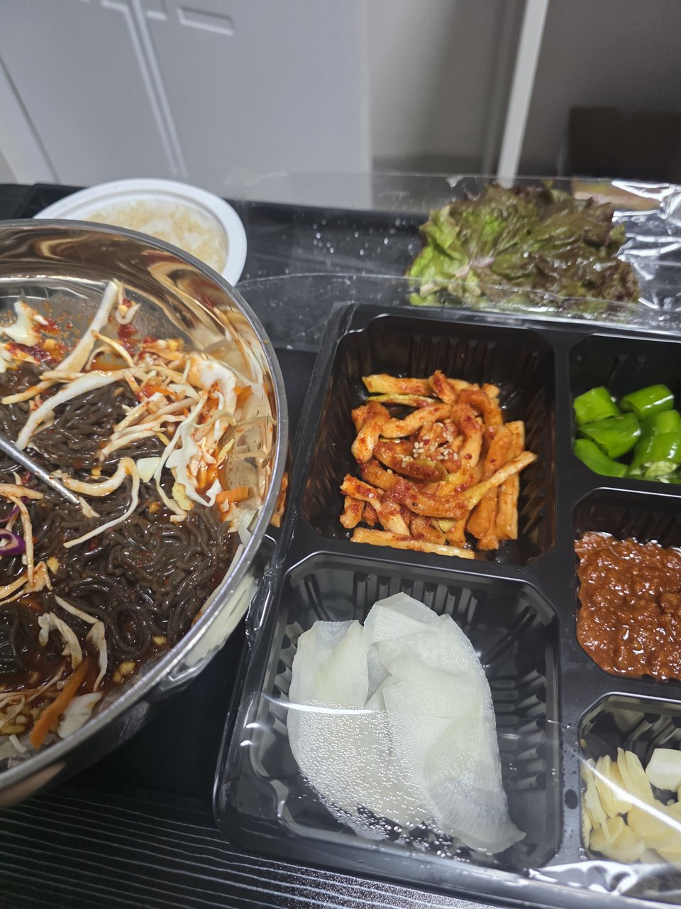 스테인리스 그릇에 비빈 막국수와 무쌈, 쌈장, 마늘, 고추, 상추