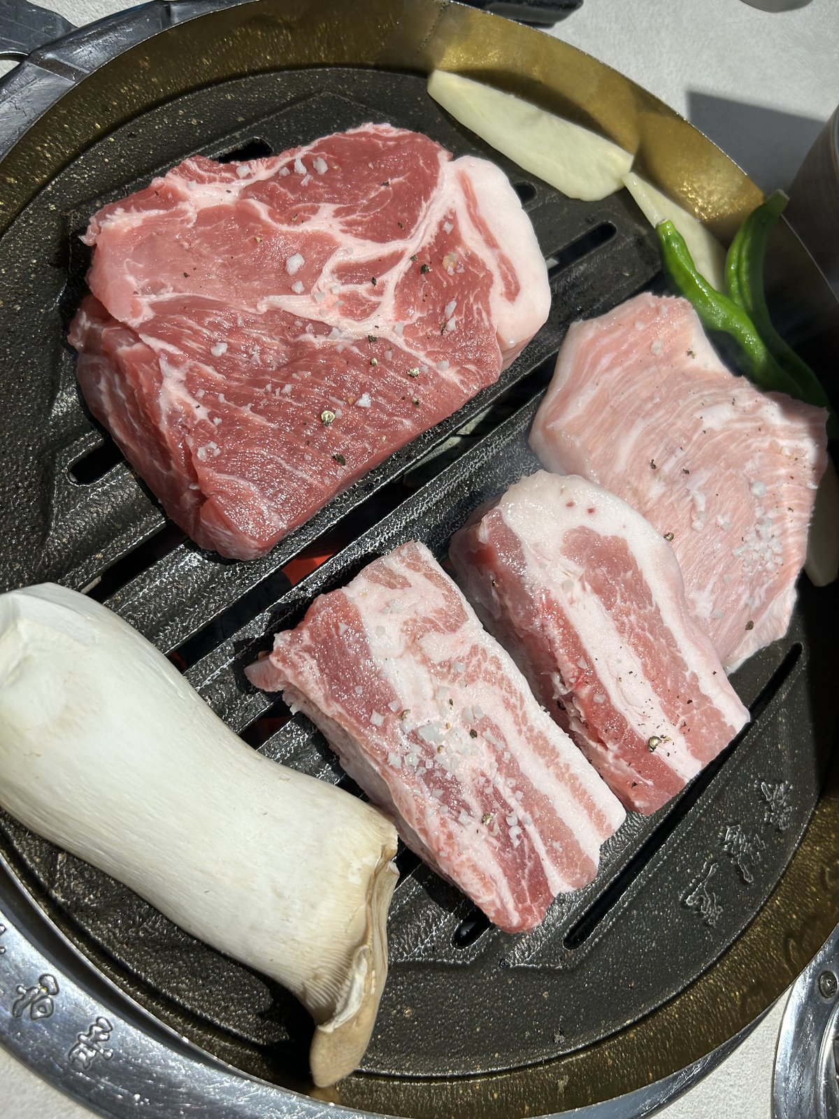 둥근 불판에 올린 생 삼겹살과 목살, 새송이버섯