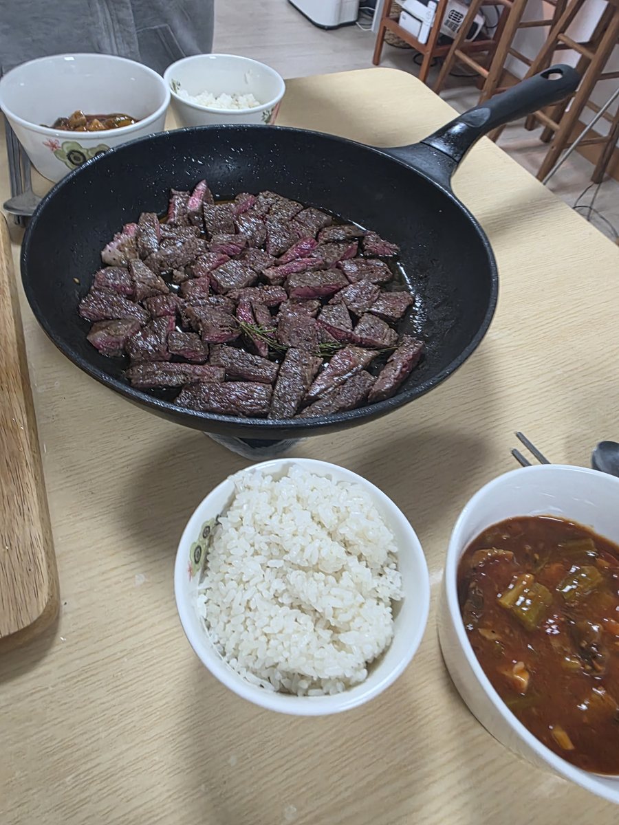 무쇠 팬에 썰어 담은 스테이크와 밥 한 공기, 찌개
