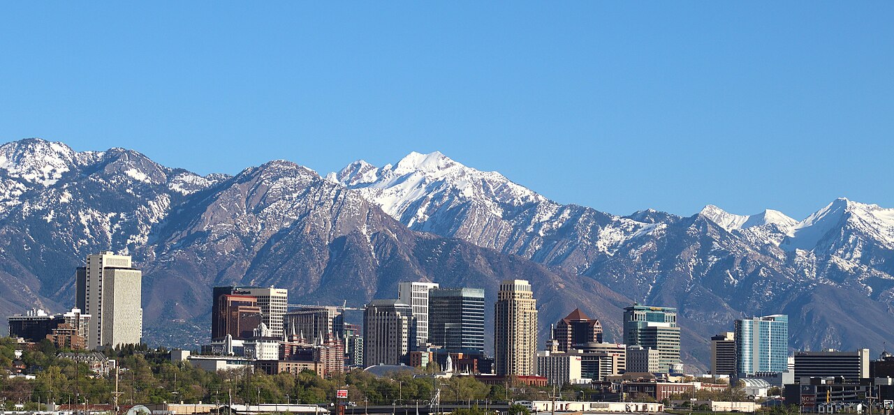 Downtown Salt Lake City, Utah, in front of the snow-capped Wasatch Range under a clear sky, 맑은 하늘 아래 눈 덮인 와사치 산맥을 뒤로한 유타 솔트레이크 시내