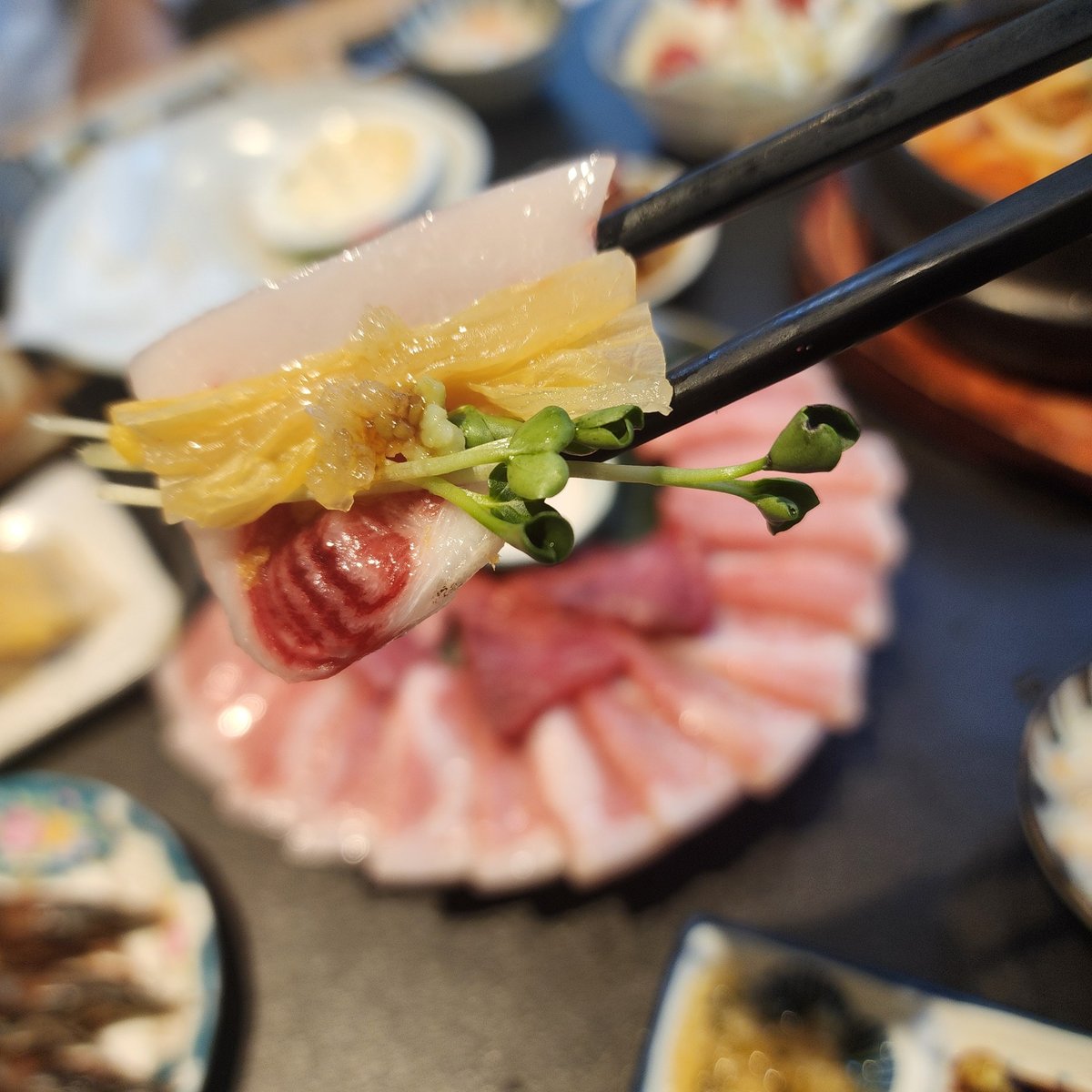 참치한점 참치 한 점을 젓가락으로 집어 올린 모습, 절임과 무순을 함께 올려 먹는다