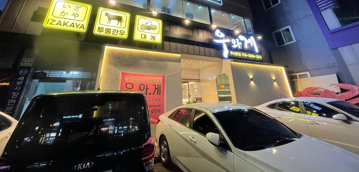 연산동 우와게 가게 정면, 이자카야 투뿔한우 대게 간판 세 개와 우와게 간판이 켜진 저녁