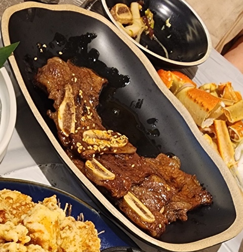검은 접시에 담긴 우와게 특제소스 LA갈비, 깨가 뿌려진 갈빗대