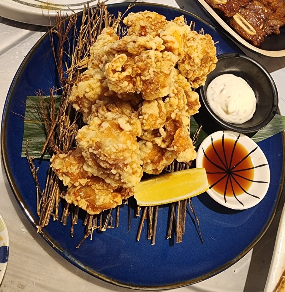 파란 접시에 수북이 담긴 우와게 치킨 가라아게와 레몬, 타르타르 소스